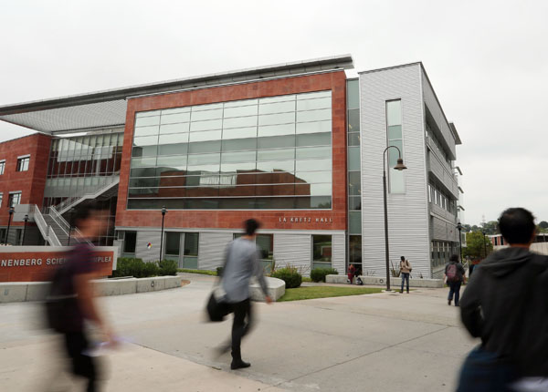 A student walking down a concrete walkway on campus.