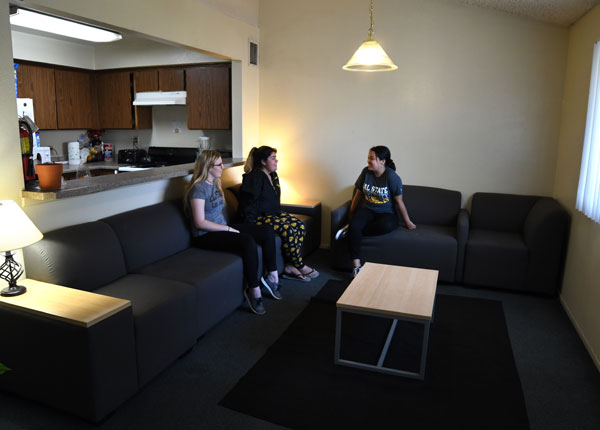 Students sitting on a couch talking to each other.