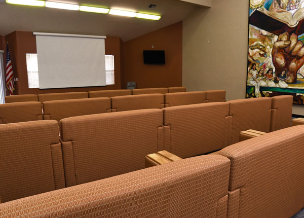 Many rows of couches with a projector screen in front of them.