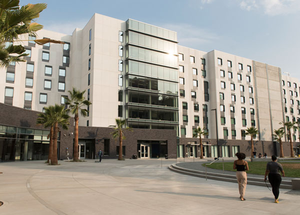 People walking in front of a large modern housing complex.