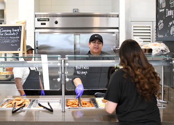 A person serving food from behind a counter.