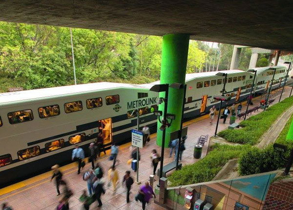 A train stop with many people waiting for the train.