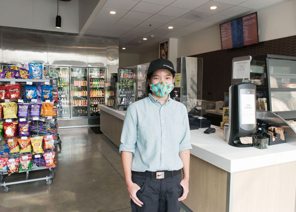 A market employee stands in front of a cash register.