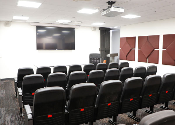 A row of seats in front of a hanging TV.