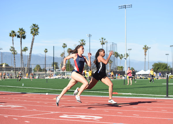 Runners running on a track on a sunny day.