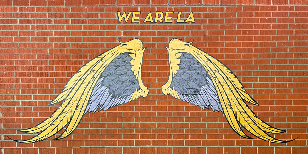 Artistic interpretation of wings on a white wall outside of the Cal State LA library..