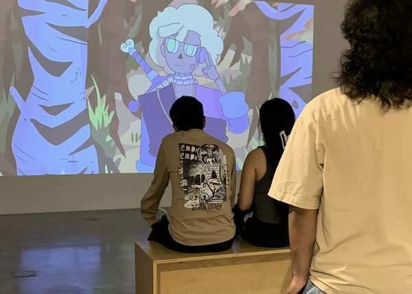 A group of people watching a film projected onto a wall.