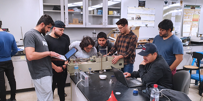 Group of Civil Engingeering Graduate students working together on a machine for their project