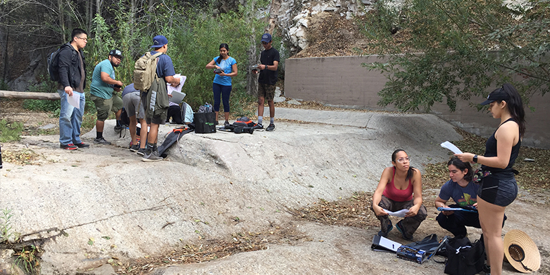 Two groups of Cal State LA graduate students working at a project on a concrete site