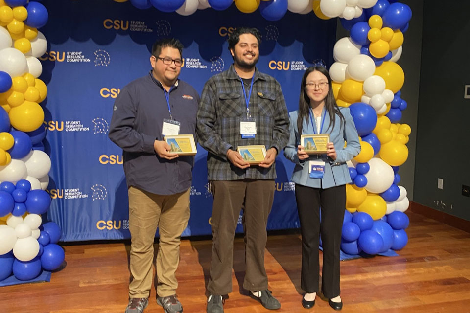 Three students pose for photo with their awards.