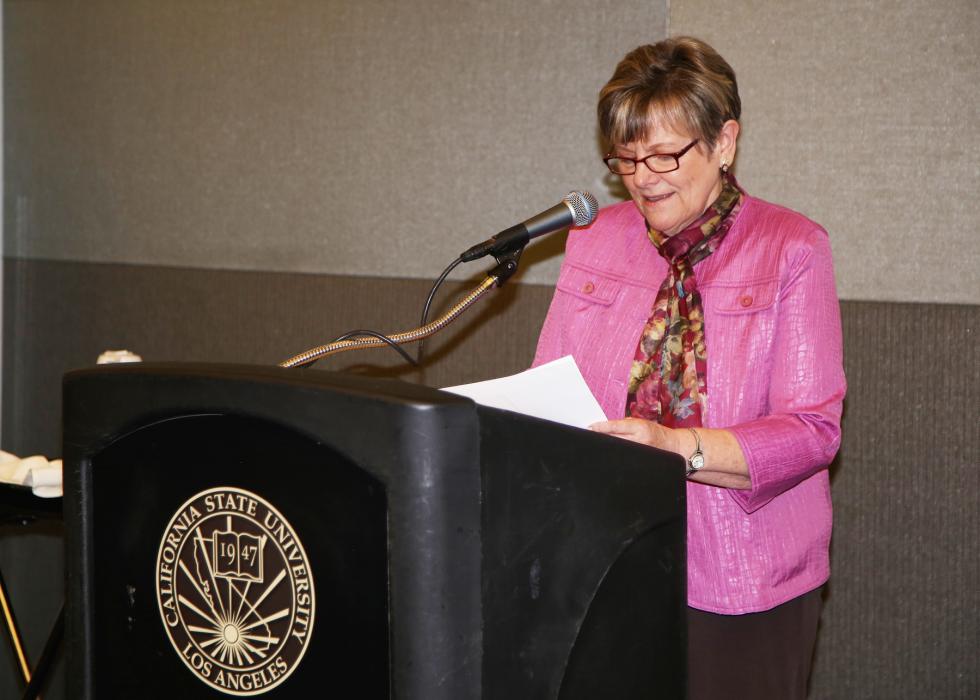 Diane Klein woman in jacket with scarf who is standing at podium