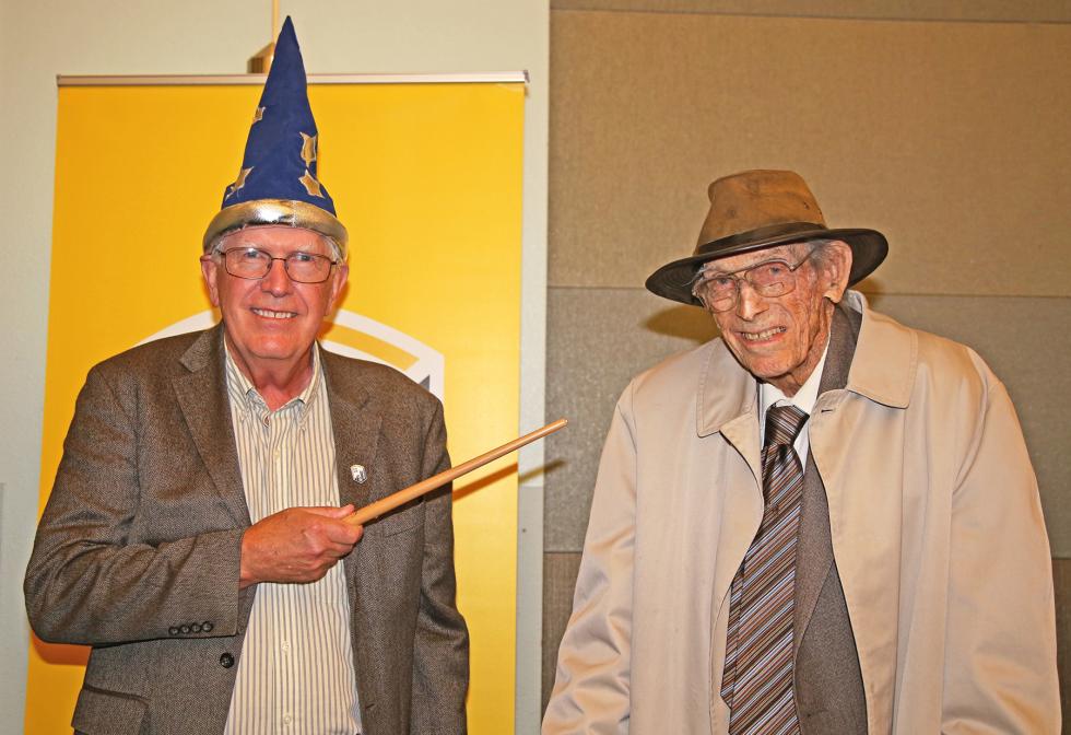 John Clema:man wearing wizard hat, pointing stick to Len Mathy