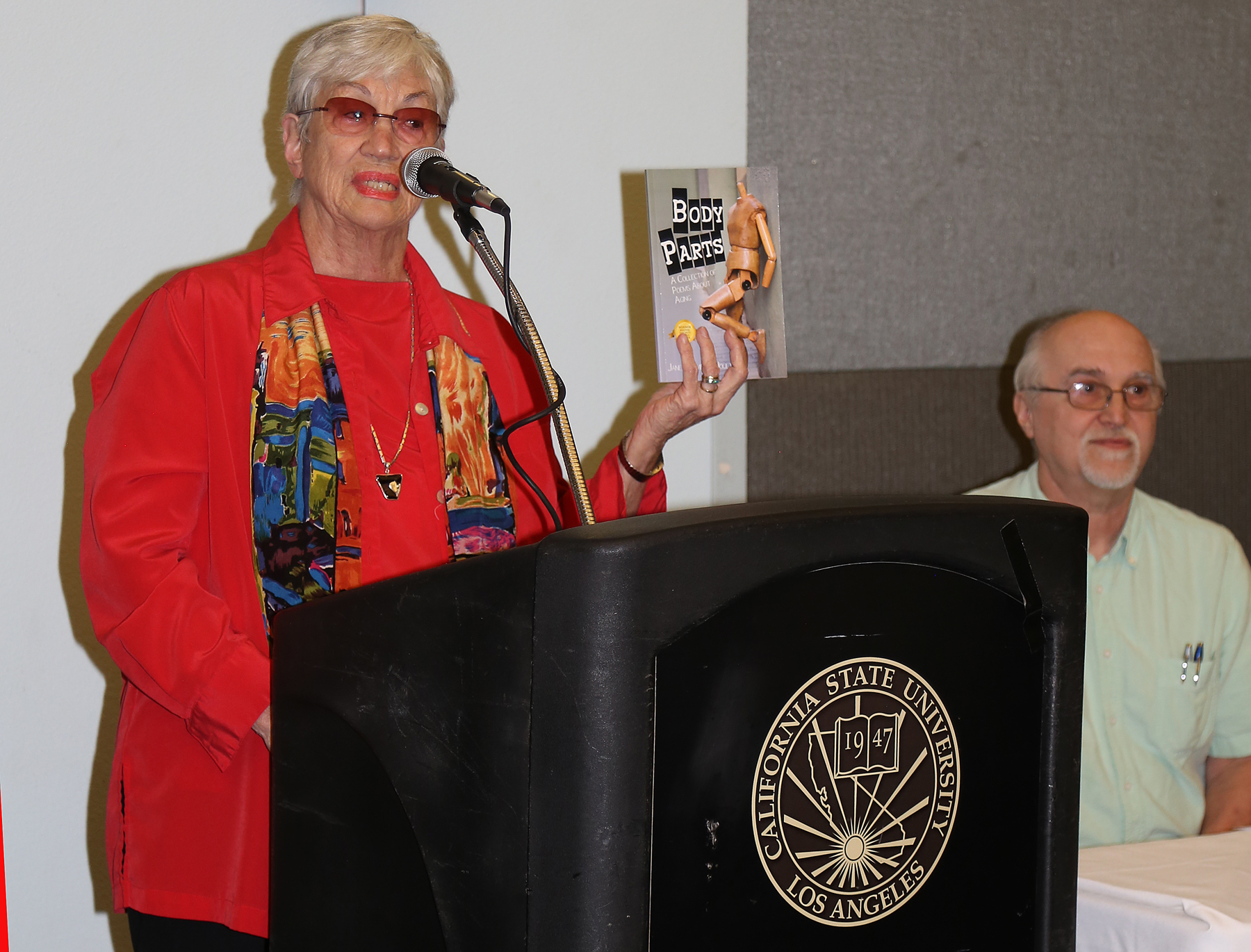 Professor holding body parts book and standing at podium