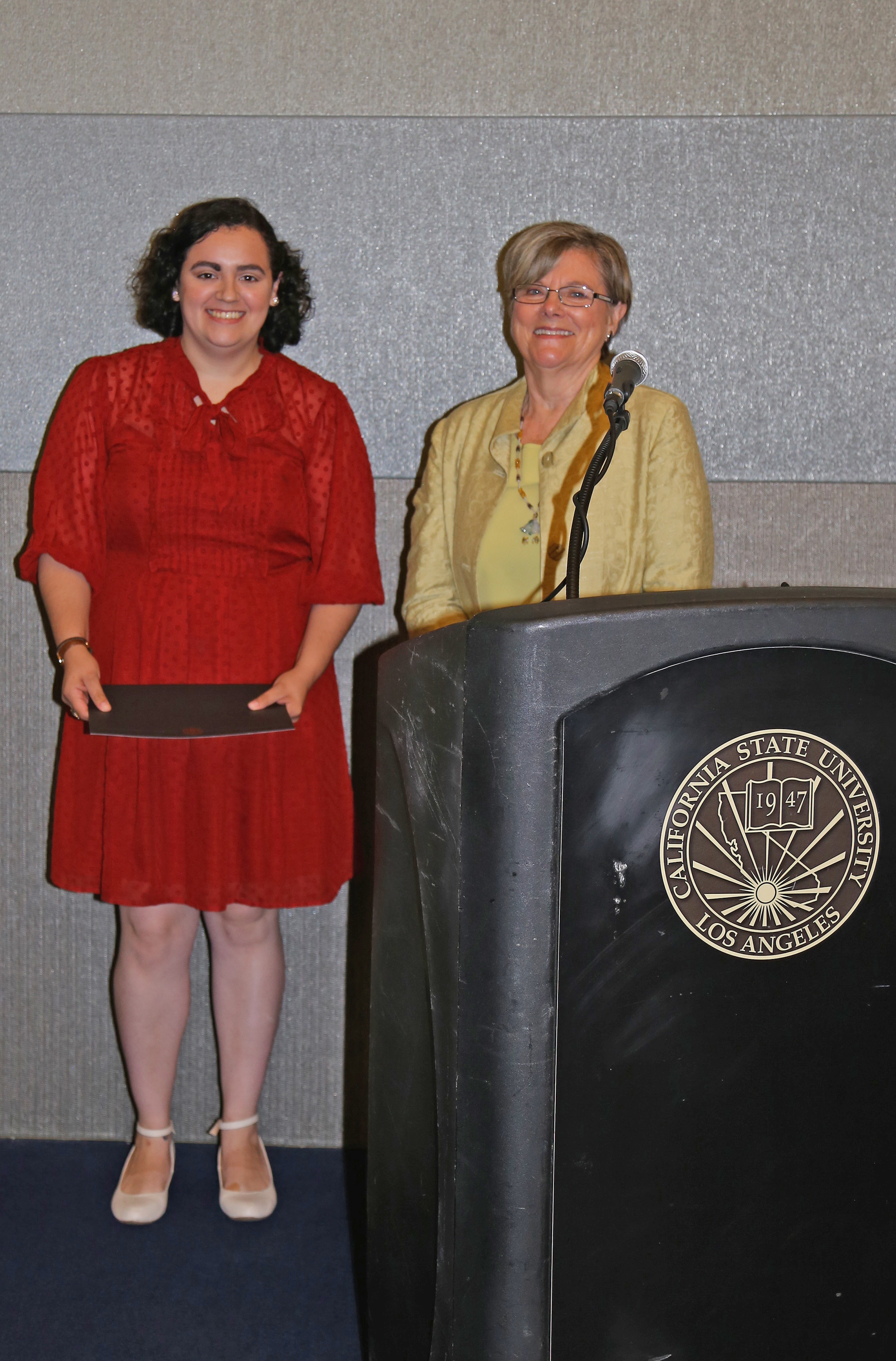 student and professor at podium at fall 2017 luncheon