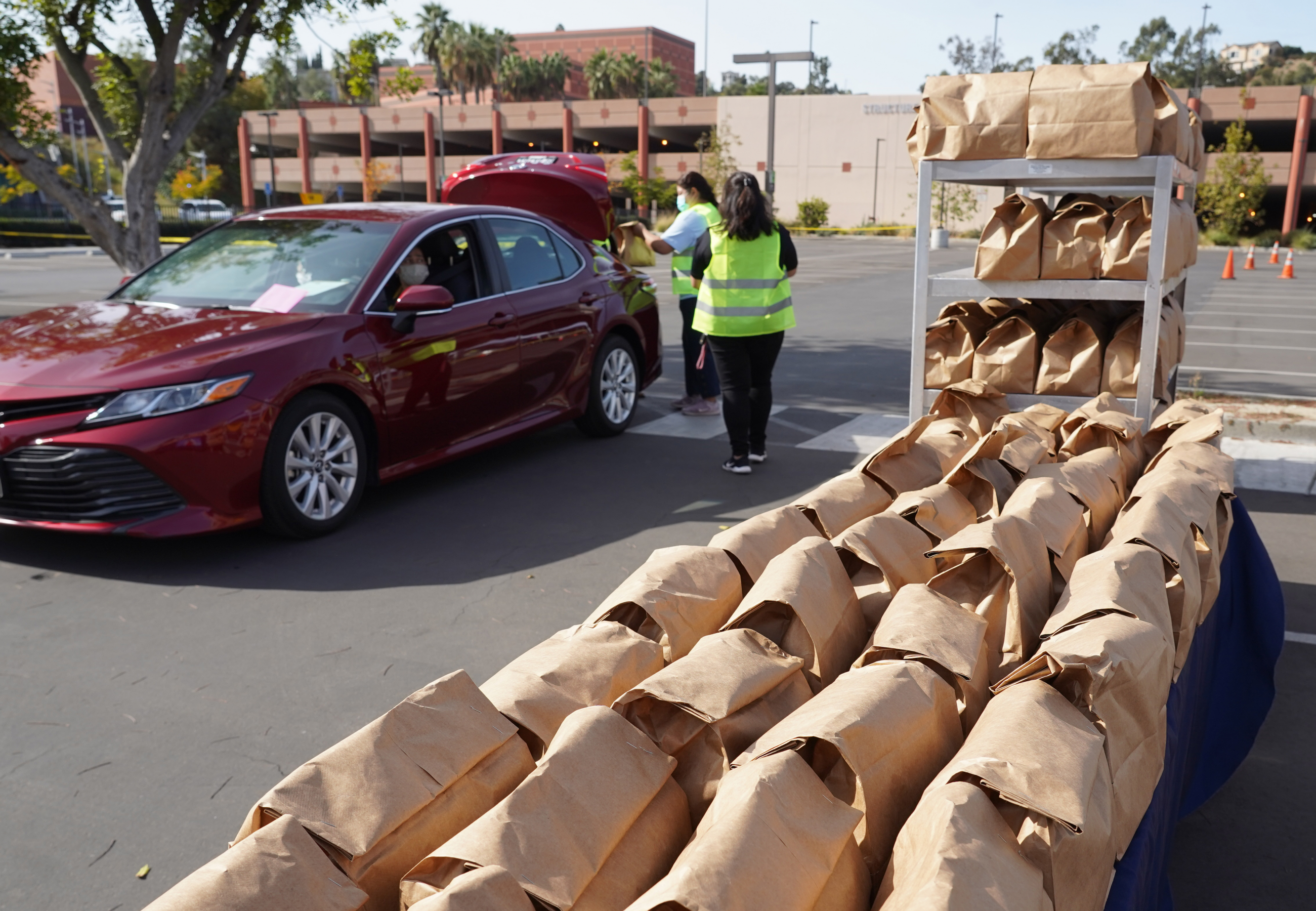 Volunteers load grocery bags into a car