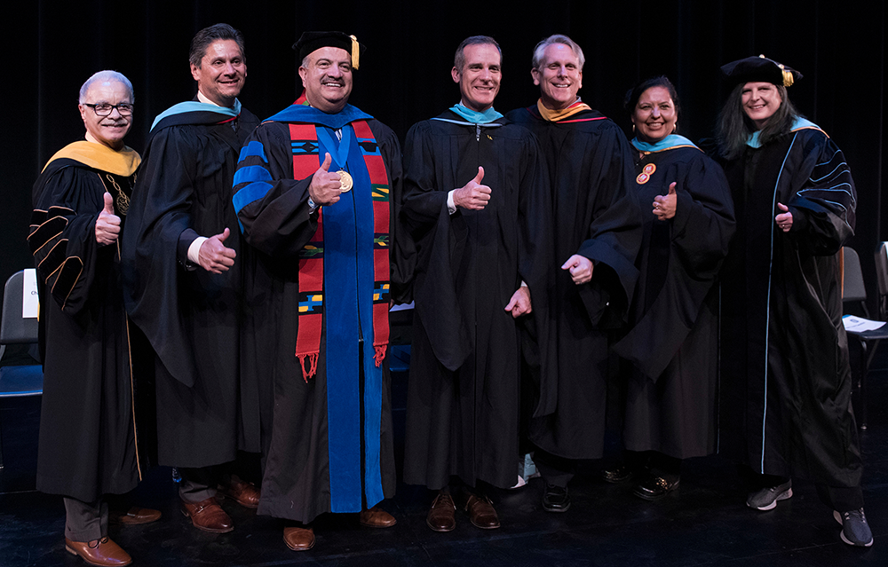 Group of administrators and officials onstage showing thumbs up sign