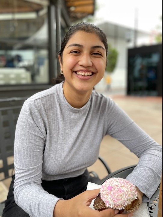 Smiling woman with black hair wearing a light grey sweater