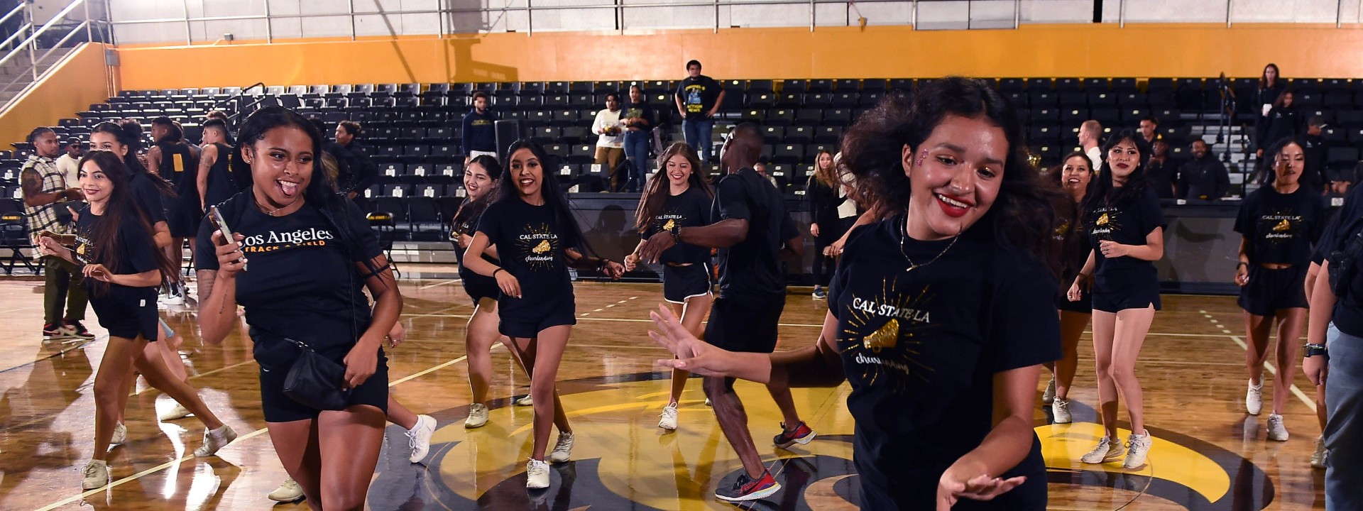 Dance team in identical t-shirts and shorts smiling mid-dance step.
