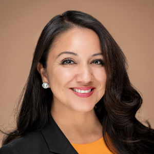 Woman with dark hair and black jacket and mustard shirt