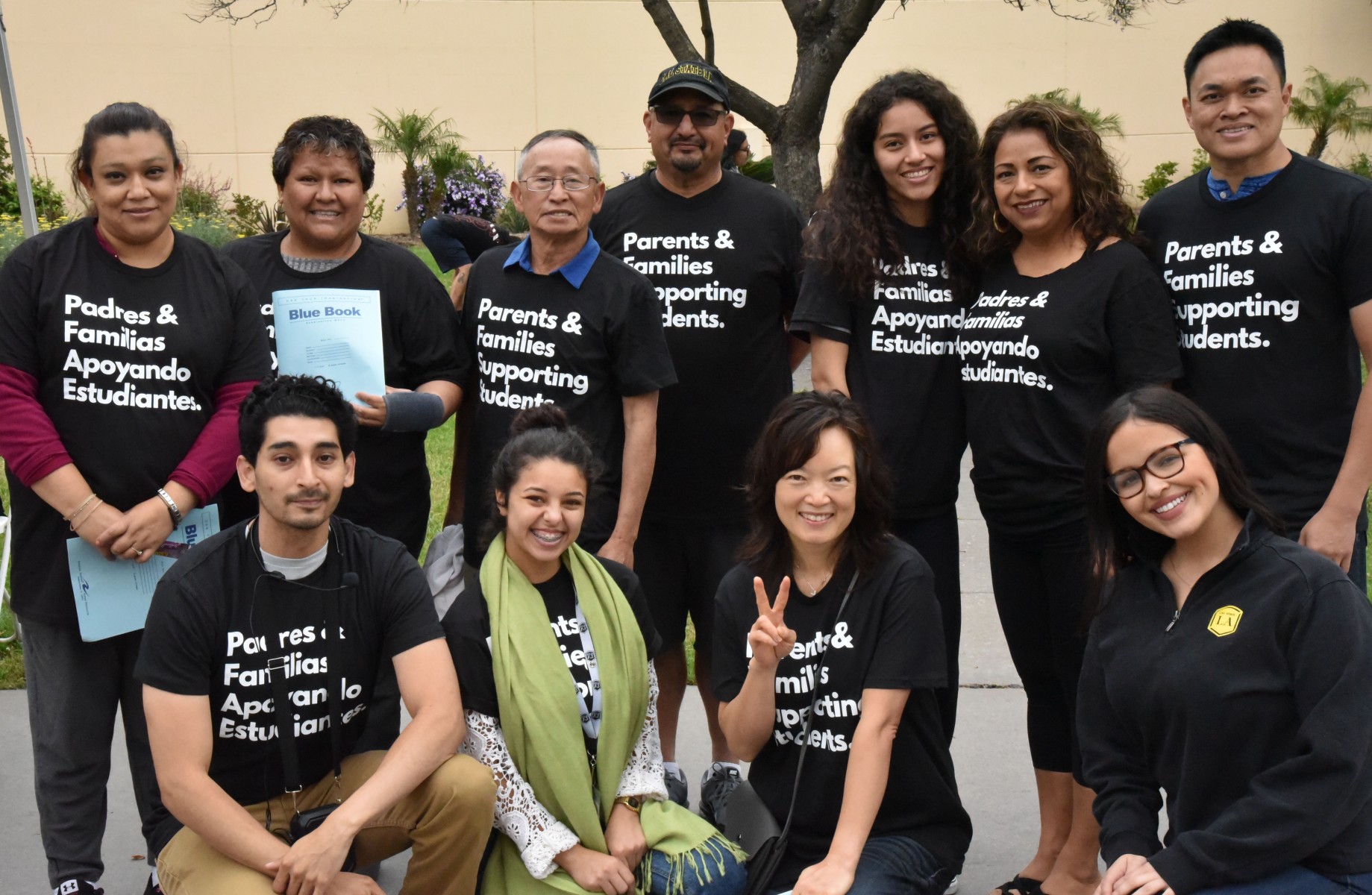 Parents, staff and students pose for a photo after handing out college blue books.