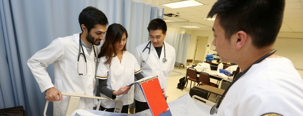 undergraduate nursing students examine a dummy patient in a Simulation Lab. 