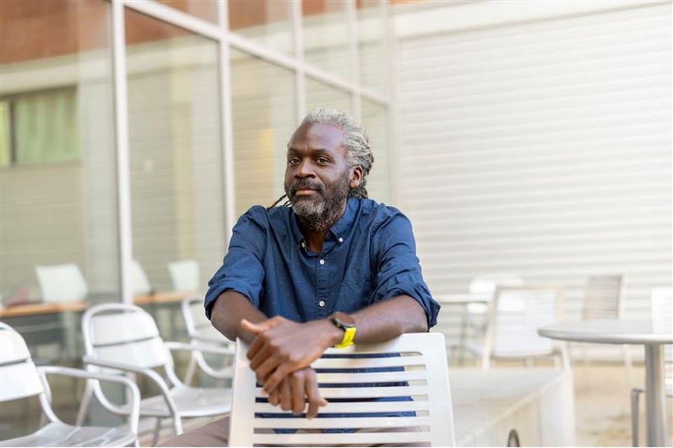 Man posing on chair wearing blue button up