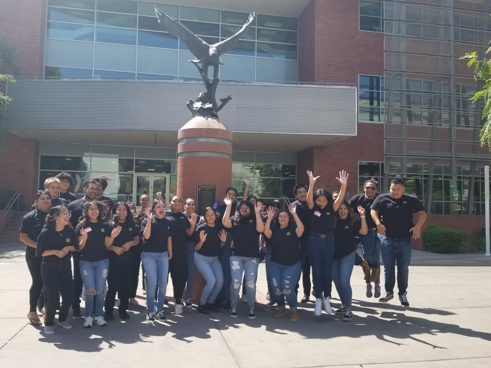 Peer leaders jumping in front of the golden eagle statue