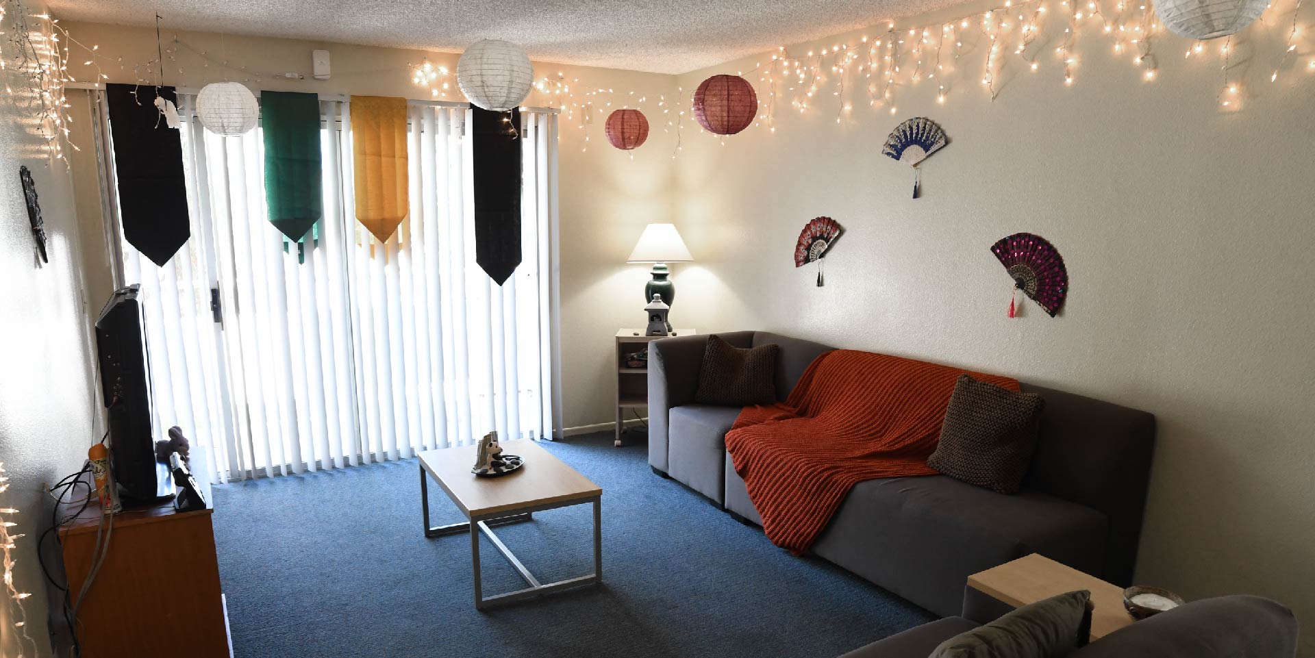 Living area with two chairs and two lamps, couch and balcony in the background.