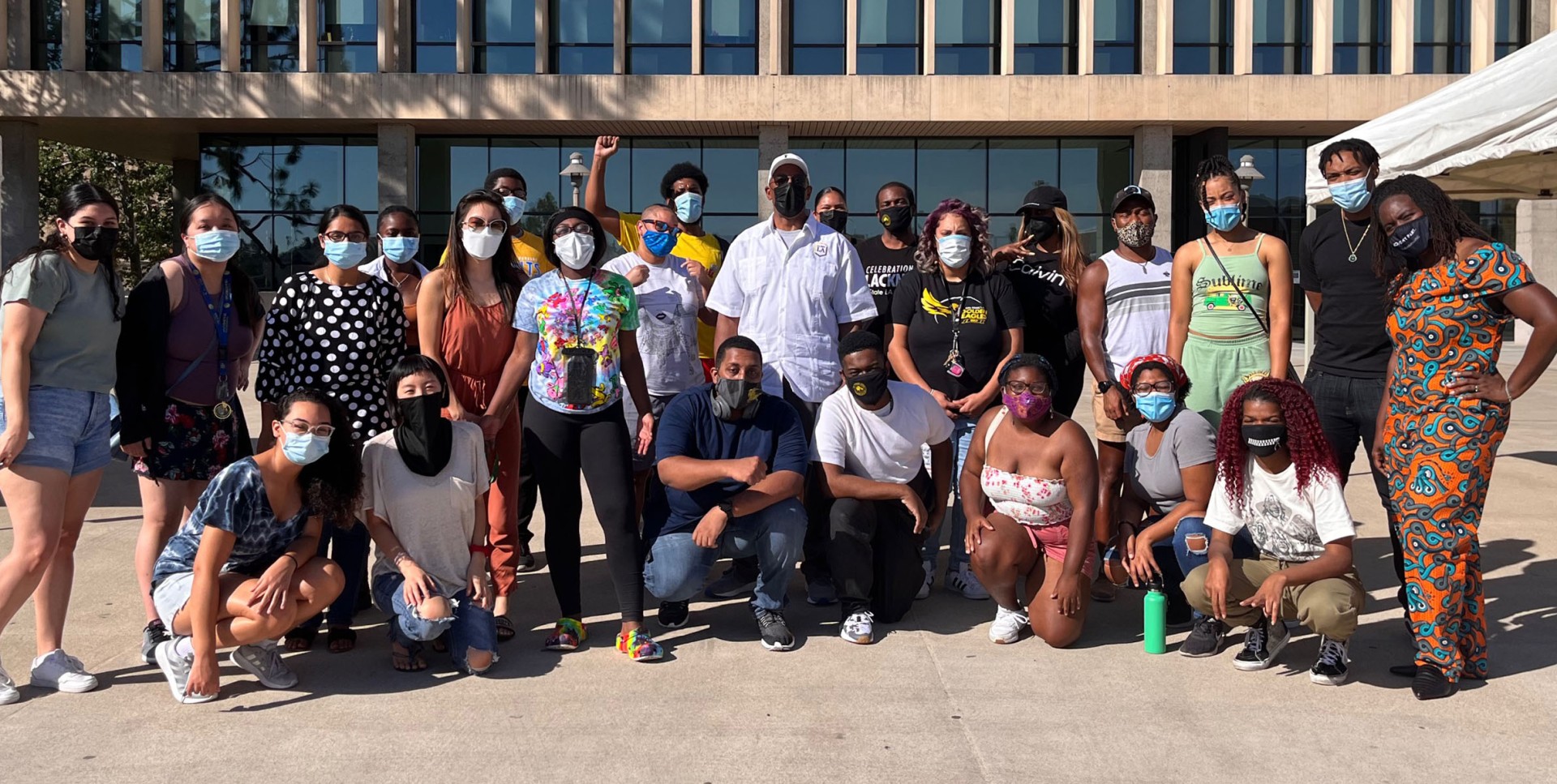 large group of people outside wearing facial coverings.