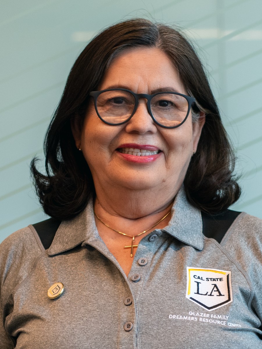 Person with short hair and shoulder-length glasses smiling.