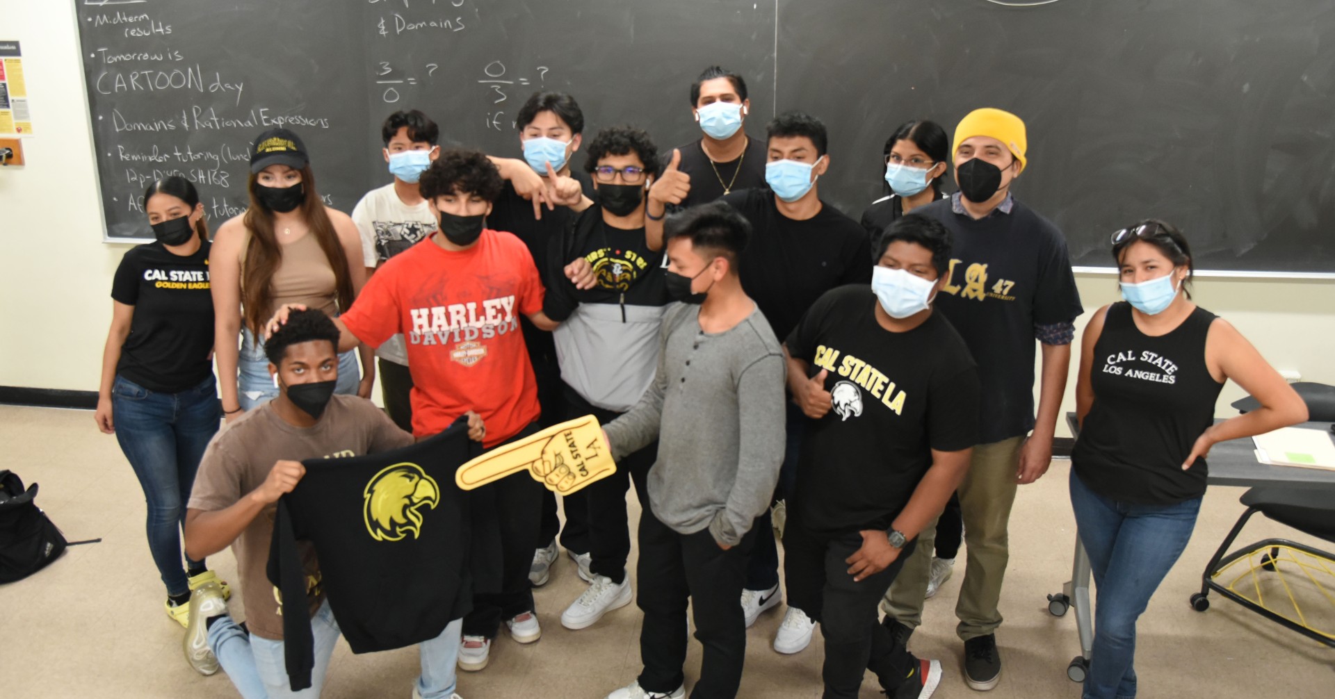 A group of students wearing facial coverings posing inside a classroom.