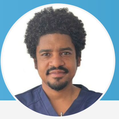 Man with black hair and black facial hair wearing a blue top.