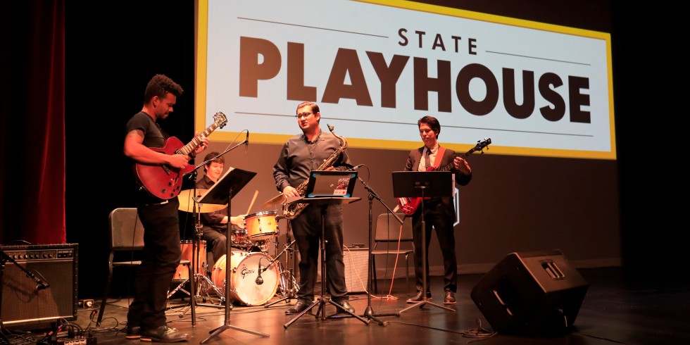 Three students play instruments on stage at State Playhouse