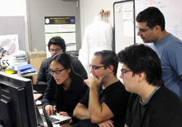 students surround faculty work on computer