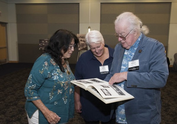 Three alumni from the class of 1972 look over a yearbook