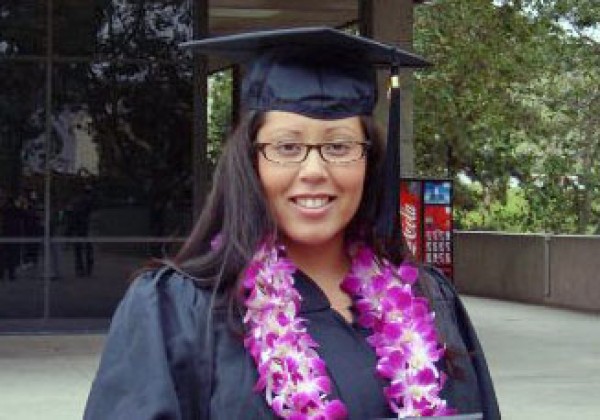 A person wearing a cap and gown smiling.