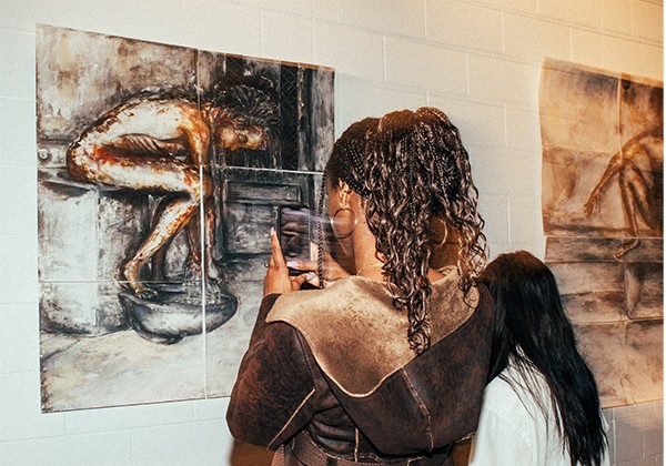 Woman taking picture of art piece created by inmates