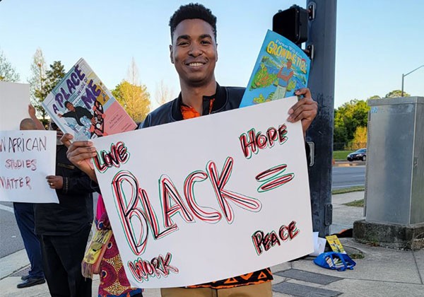 PRince Gumbi holding sign saying Black Hope = hope, peace, work and love