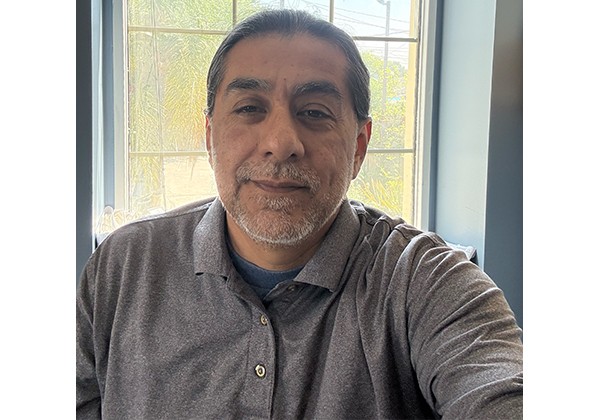 Alejandro Covarrubias sitting in front of a window wearing a polo shirt