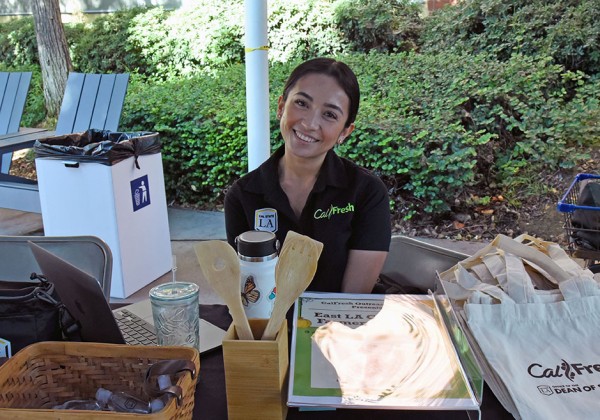 A person wearing a CalFresh polo sitting a table offering swag items.