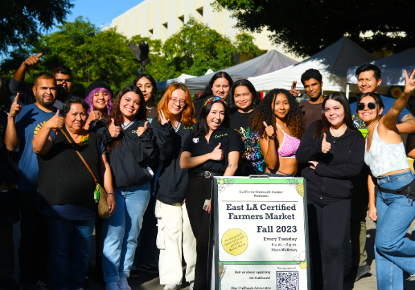 A group of people posing for a picture at the farmers market