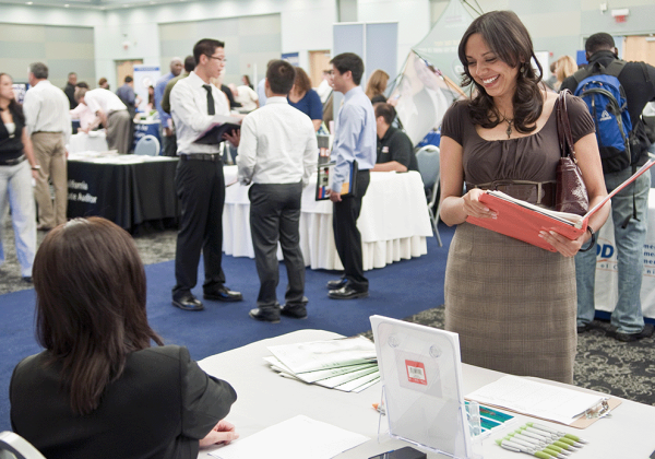 Smiling student in business clothes talks to recruiter at a career fair.