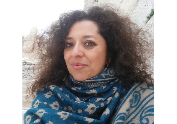 Claudia Mercado outside wearing a blue scarf and grey top