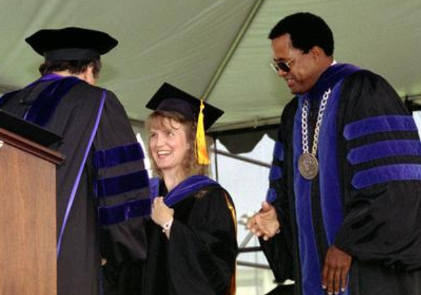 a person in a graduation gown shaking hands with another person in a cap and gown