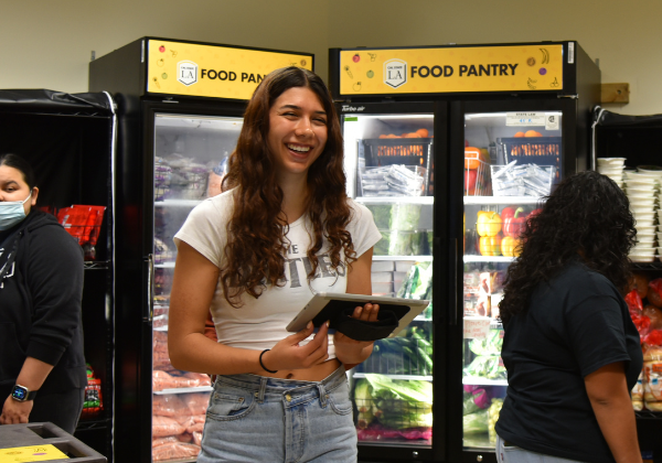 A person holding an iPad in a food pantry smiling.