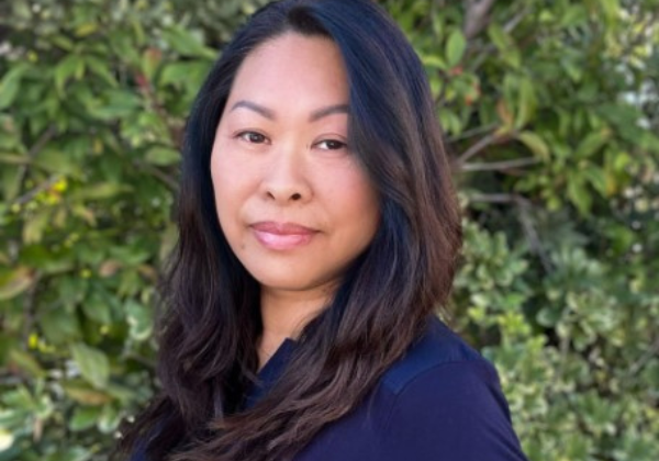 an individual in a blue shirt standing in front of bushes