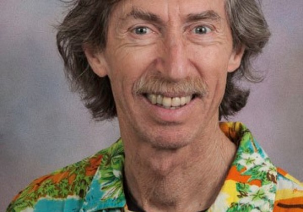 A portrait of a medium long hair professor smiling at the camera