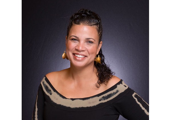 Melina Abdullah posing and smiling in front of a grey background