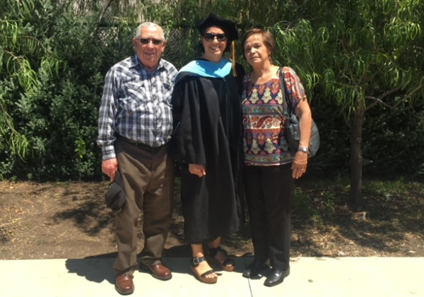 two people standing next to an individual in a graduation cap and gown