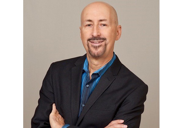 Professor Schlinger wearing a black blazer and blue shirt while smiling